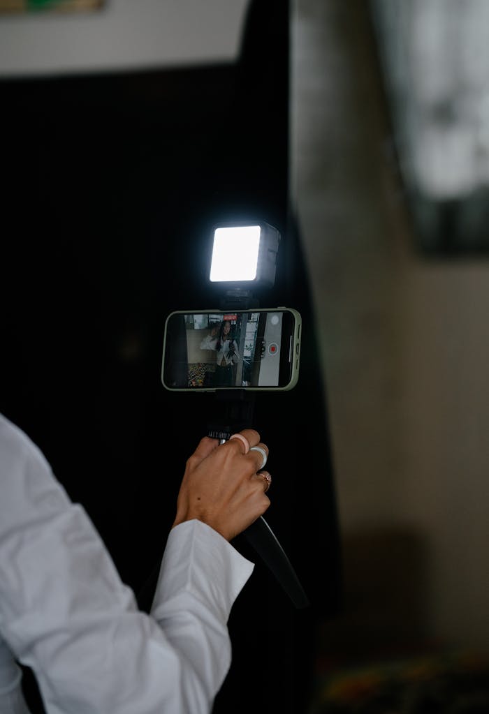 creative-03 Vlogger recording video on a smartphone with a portable LED light indoors.
