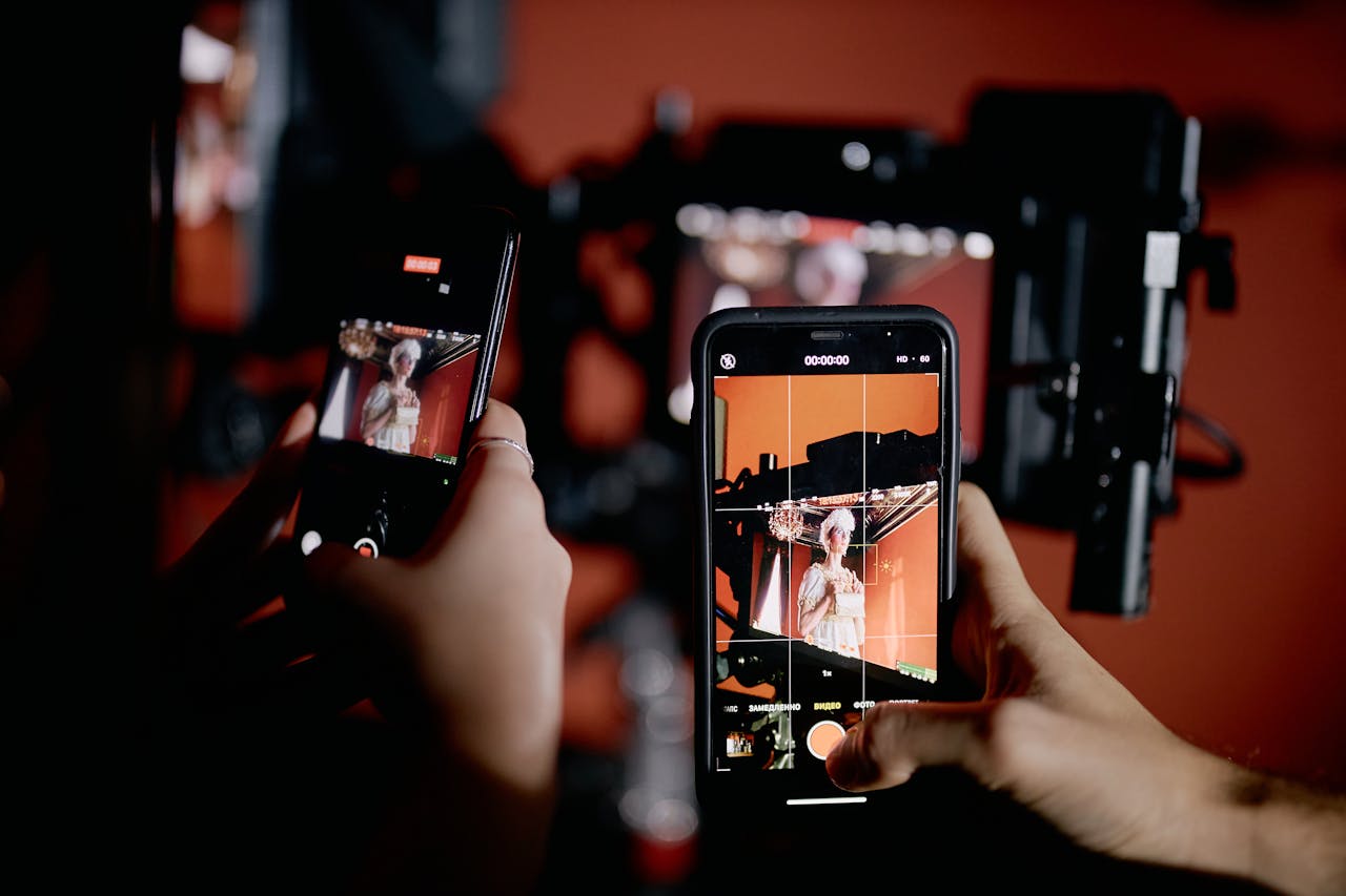 mobile-02 Hands holding smartphones recording a scene indoors with professional equipment.